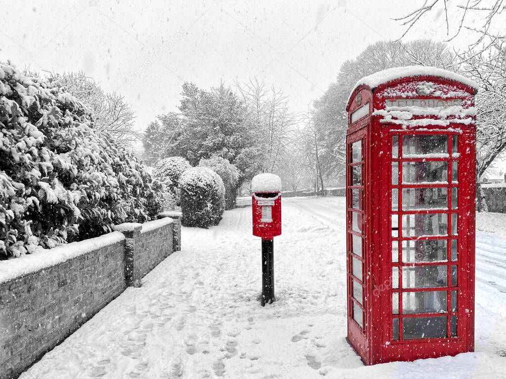 rural winter scene of village post box and phone box.  Red on black and white background