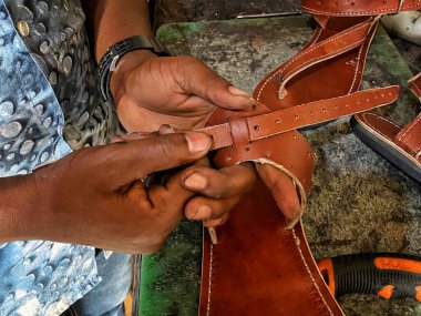 Ayakkabıcı ayakkabıcısının ayakkabıcısının atölyesindeki bir çift deri sandaleti bitirirken...