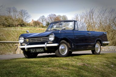 1969 Kraliyet Mavisi TriumphHerald 13 / 60 Kuzey York Moors 'daki bir köprünün yanına park etmiş.
