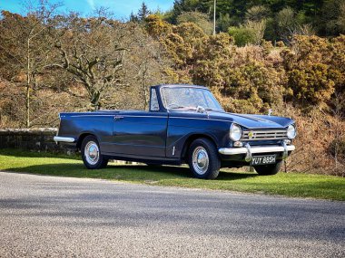 Royal Blue Triumph Herald 13 / 60 üstü açık arabası Kuzey York Moors 'ta bir köprünün yanında park halinde.