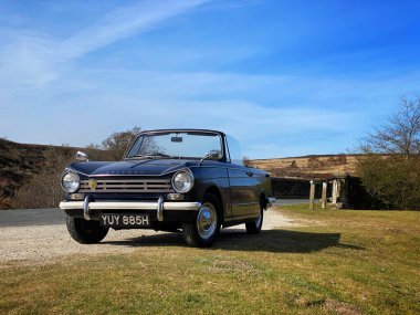 Royal Blue Triumphj Herald 13 / 60 üstü açık klasik araba Kuzey York Moors 'ta bir köprünün yanında park edilmiş.