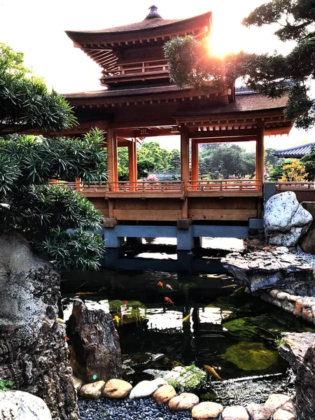 Hoonng Kong Parkı 'nda Pagoda tarzı bir köprü inşa edildi. Köprü içinde balık olan bir nehri kapsar. Güneş köprünün arkasından bakıyor. 