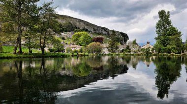 Yorkshire Dales 'deki Kilnsey Kayalığı' nın altında sakin bir balık tutma göleti.