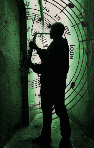 a street sax player silhouetted aganst a green light with music spilling from the sax