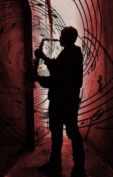 a street sax player silhouetted aganst a red light with music spilling from the instrument