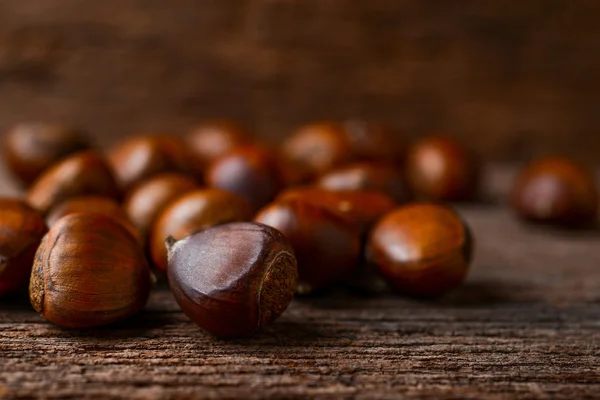 Geroosterde kastanjes op houten achtergrond — Stockfoto