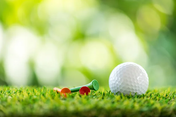 Мячик для гольфа и деревянный мяч на траве — стоковое фото