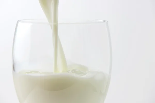 Milch in ein Glas gießen — Stockfoto