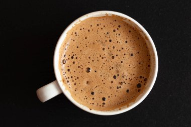 Tasarım amaçlı siyah arka planda köpüklü bir fincan kahve.