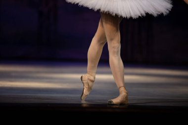 Sahnede yapayalnız dans eden balerinin yakın çekimi. Balerin bacakları yakın plan