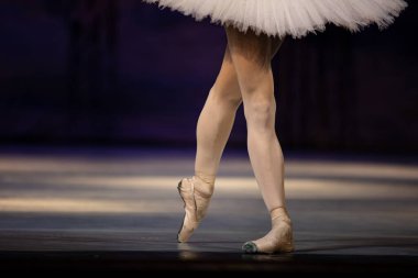 Sahnede yapayalnız dans eden balerinin yakın çekimi. Balerin bacakları yakın plan