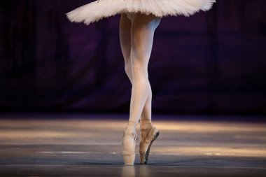Sahnede yapayalnız dans eden balerinin yakın çekimi. Balerin bacakları yakın plan
