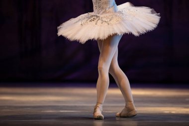 Sahnede yapayalnız dans eden balerinin yakın çekimi. Balerin bacakları yakın plan