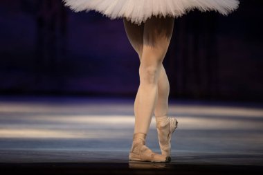 Sahnede yapayalnız dans eden balerinin yakın çekimi. Balerin bacakları yakın plan
