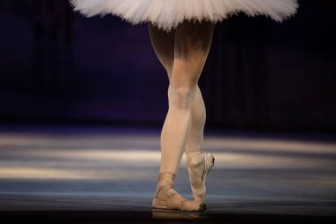 Sahnede yapayalnız dans eden balerinin yakın çekimi. Balerin bacakları yakın plan