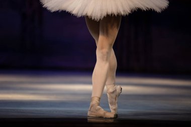 Sahnede yapayalnız dans eden balerinin yakın çekimi. Balerin bacakları yakın plan