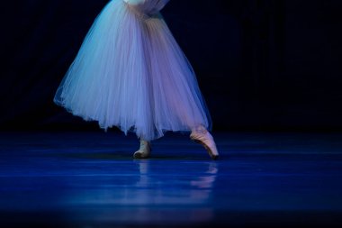 Sahnede yapayalnız dans eden balerinin yakın çekimi. Balerin bacakları yakın plan