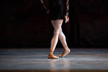 Sahnede yapayalnız dans eden balerinin yakın çekimi. Balerin bacakları yakın plan