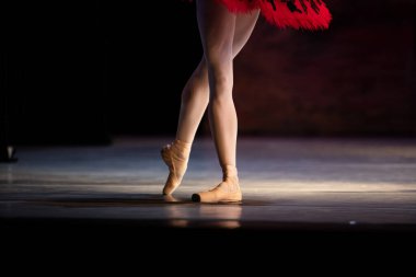 Sahnede yapayalnız dans eden balerinin yakın çekimi. Balerin bacakları yakın plan