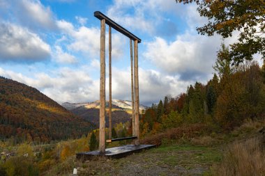 Panoramik sonbahar dağ manzaralı dev ahşap salıncak.