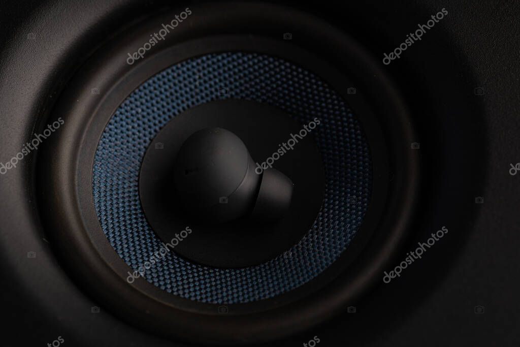 Close Up Wireless Earbuds Resting Inside Speaker Woofer