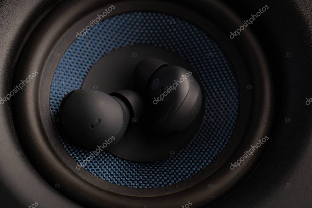 Close Up Wireless Earbuds Resting Inside Speaker Woofer