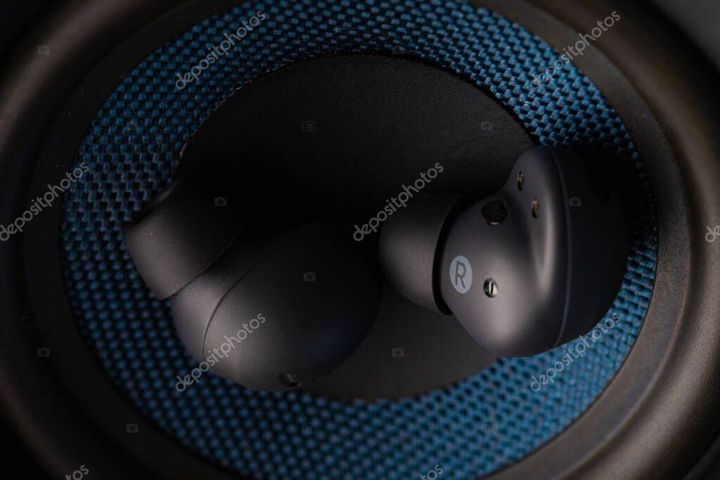Close Up Wireless Earbuds Resting Inside Speaker Woofer