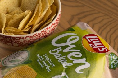 Lviv, Ukrayna - 16 Kasım 2025: Lay 's Oven Fırınlanmış Yoğurt Odun Masasında Paketleme ile bir kasede cips