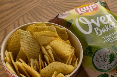 Lviv, Ukrayna - 16 Kasım 2025: Lay 's Oven Fırınlanmış Yoğurt Odun Masasında Paketleme ile bir kasede cips