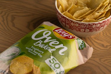 Lviv, Ukrayna - 16 Kasım 2025: Lay 's Oven Fırınlanmış Yoğurt Odun Masasında Paketleme ile bir kasede cips
