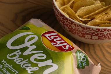 Lviv, Ukrayna - 16 Kasım 2025: Lay 's Oven Fırınlanmış Yoğurt Odun Masasında Paketleme ile bir kasede cips