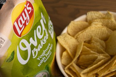 Lviv, Ukrayna - 16 Kasım 2025: Lay 's Oven Fırınlanmış Yoğurt Odun Masasında Paketleme ile bir kasede cips