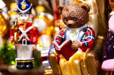 Koltukta kitap okuyan oyuncak ayının dekoratif Noel süsü.