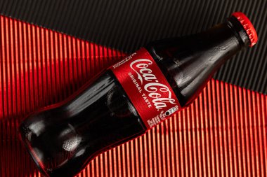 Lviv, Ukrayna - 13 Mart 2026: Kırmızı desenli arka plan üzerine soğutulmuş Coca-Cola Şişesi