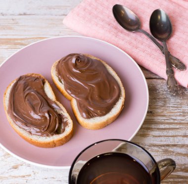 Çikolatalı fındıklı kremayı bir bardak çayla birlikte bir dilim ekmeğe sürün. Çikolatalı ve fındıklı kahvaltı ve bir fincan çay..