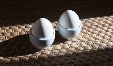 Hasır bir peçetenin arka planında keskin gölgeler olan bir tezgahta yumurtalar.