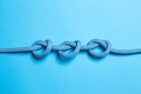 Three knots on a rope on a blue background.