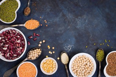 Koyu bir arka planda çeşitli mısır gevreği ve baklagiller. Mercimek, kırmızı fasulye, kinoa, nohut, püre, bezelye, darı, karabuğday. Glütensiz ürünler. Üst görünüm, alanı kopyala.