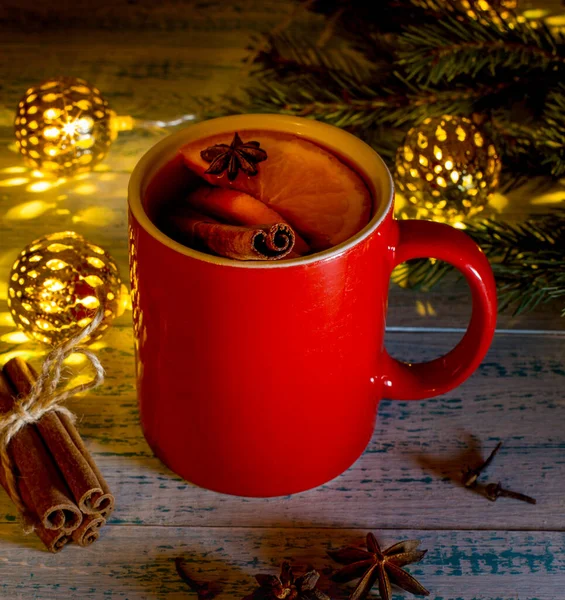 用橙子 茴香和肉桂装饰在圣诞树枝条和花环的背景上的热葡萄酒 温暖的圣诞饮品节日气氛 — 图库照片