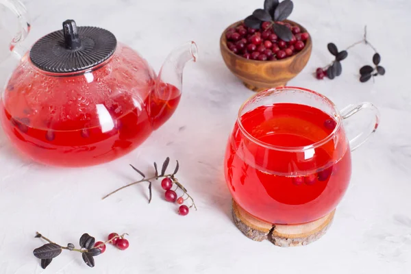 一杯热红莓茶和一个浅色背景的茶壶 用浆果加热和治疗茶 新年的饮料 一个温馨的夜晚 — 图库照片