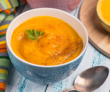 Geleneksel sonbahar balkabağı çorbası püresi mavi arka planda. Vejetaryen yemeği..