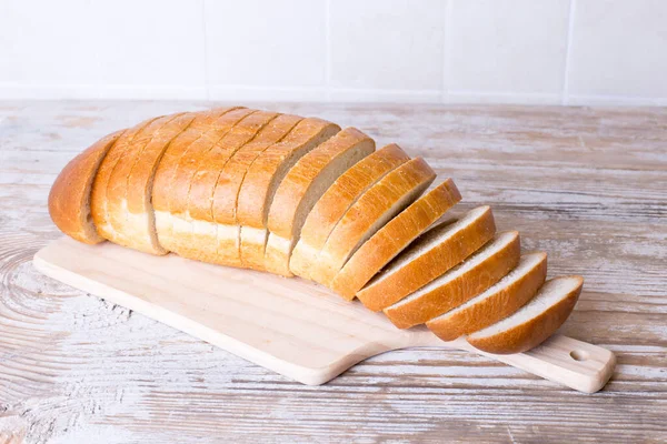 Pão branco fatiado em uma tábua de madeira. — Fotografia de Stock