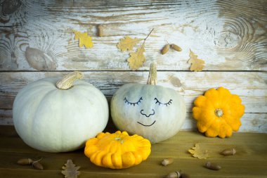 Ahşap arka planda yaprakları olan sonbahar balkabakları. Sıcak bir sonbahar konsepti.