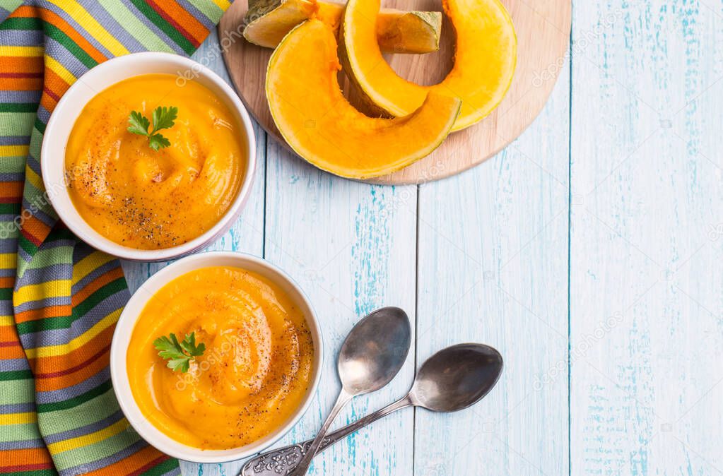 Traditional autumn pumpkin soup-puree on a blue background. Vegetarian delicious food.