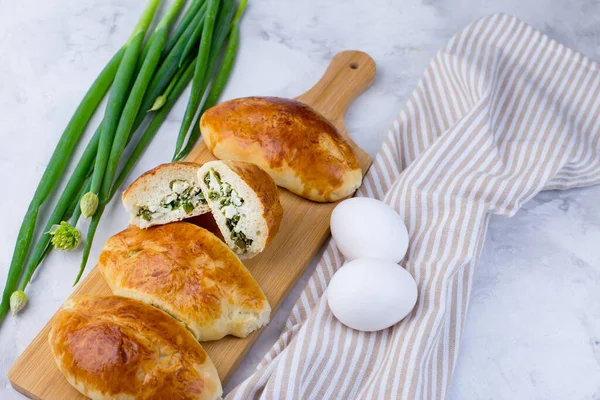 Delicious little pies with green onion and egg. Traditional Russian cuisine. Homemade cakes. A plate of pies on a light background. close-up