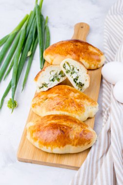 Yeşil soğanlı ve yumurtalı lezzetli küçük turtalar. Geleneksel Rus mutfağı. Ev yapımı kekler. Hafif arka planda turtaları olan tahta bir tahta..