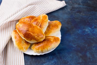Yeşil soğan ve yumurtalı lezzetli küçük turtalar. Geleneksel Rus mutfağı. Ev yapımı kekler. Koyu arkaplanda bir tabak turta..