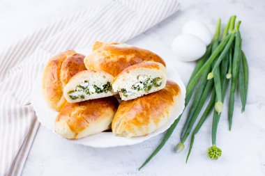 Yeşil soğanlı ve yumurtalı lezzetli küçük turtalar. Geleneksel Rus mutfağı. Ev yapımı kekler. Hafif arka planda turtaları olan tahta bir tahta..