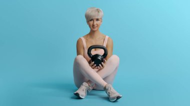 Güzel, atletik bir kadın elinde siyah, ağır bir kettlebell, fotokopi, uzay boşluğu...