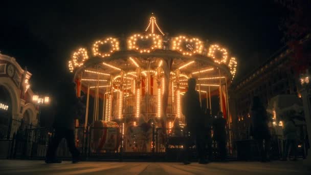 Стара карусель з яскравим світлом обертається в міському парку з людьми. повільно-швидко. Москва, Росія, 09.23.2021 — стокове відео